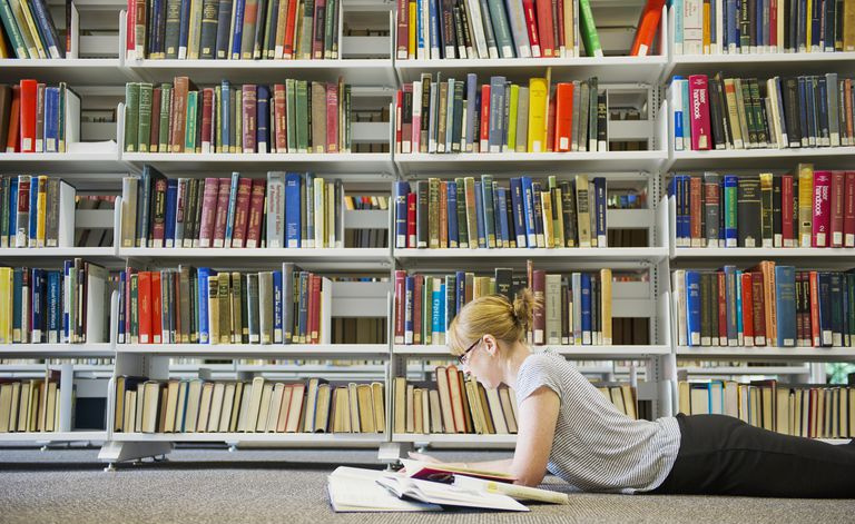 Kaukaska kobieta studiuje na podłodze biblioteki
