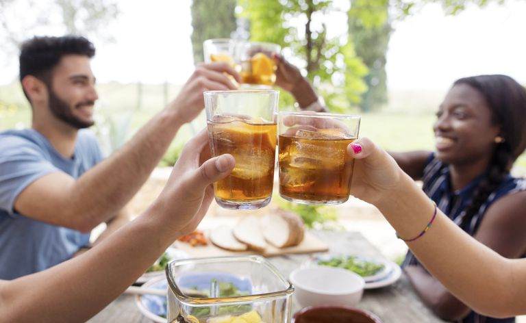 Amis grillant des verres de thé glacé à la table extérieure
