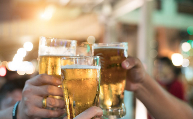 Amis portant un toast avec des verres de bière légère au pub.