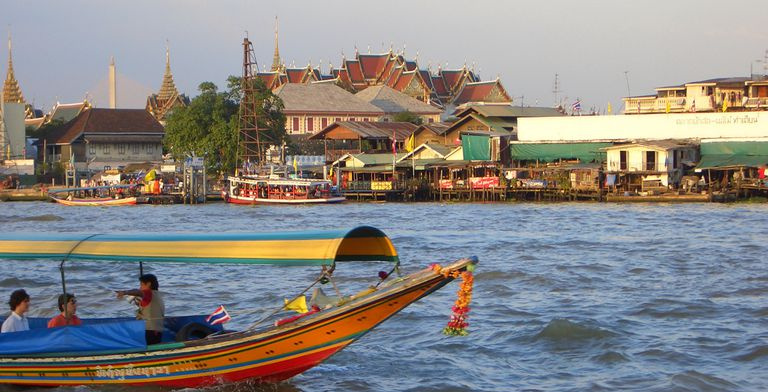 Littoral thaïlandais montrant un bateau et une architecture terrestre pendant une journée nuageuse.