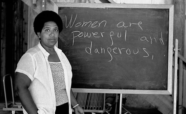 Audre Lorde in piedi vicino a una lavagna con la dichiarazione,