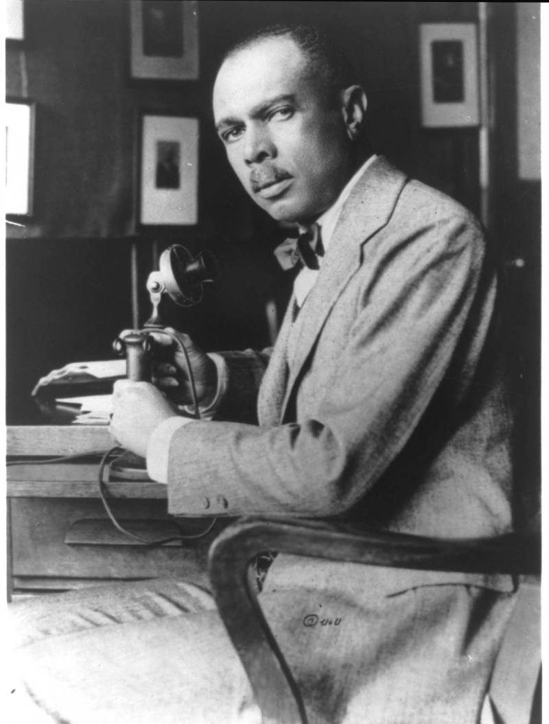 James Weldon Johnson seduto alla sua scrivania, fotografia in bianco e nero.