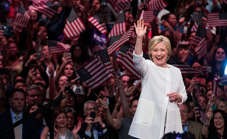 Hillary Clinton salue devant une foule de personnes brandissant des drapeaux américains