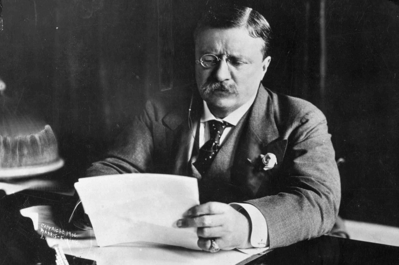 Theodore Roosevelt leyendo documentos en su escritorio