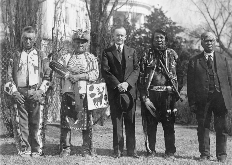 Svart-hvitt bilde fra 1924 av USAs president Calvin Coolidge med fire Osage-indianere foran Det hvite hus