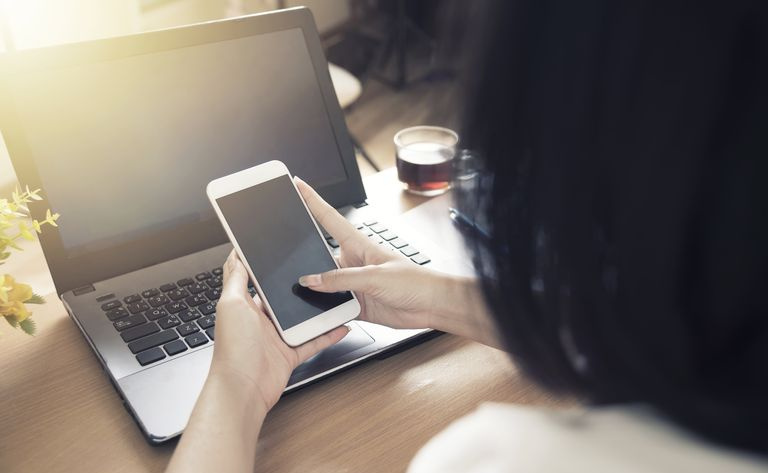 kobieta korzystająca z telefonu komórkowego i komputera