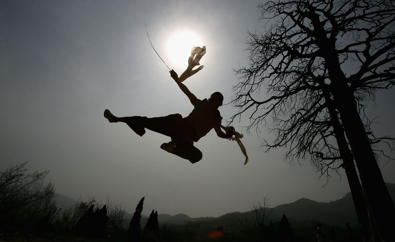 Silhouette eines Mönchs, der Zwillingsschwerter zu halten scheint.