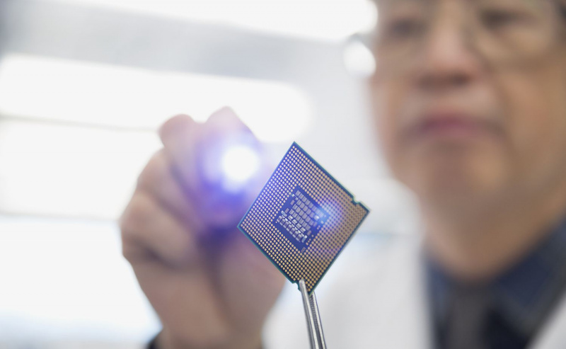 Fokussierter Ingenieur untersucht Mikrochip mit Taschenlampe