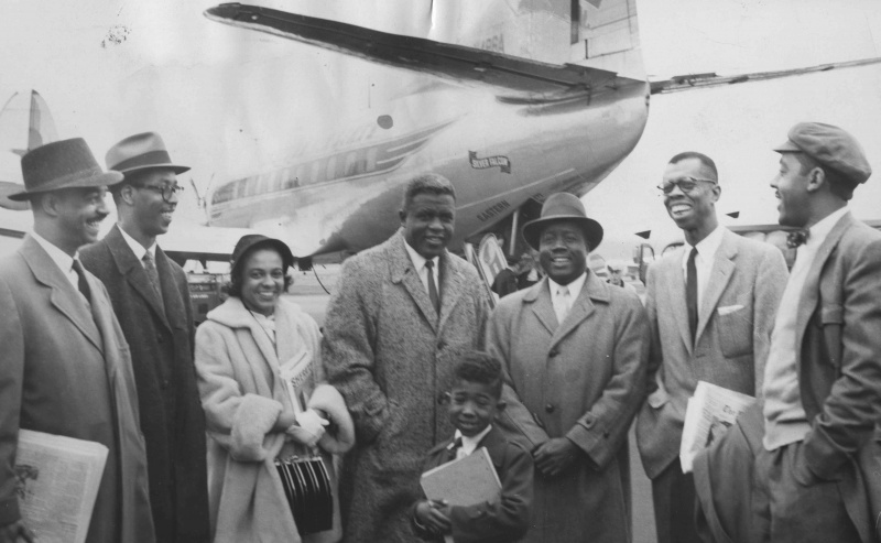 Jackie Robinson står sammen med en gruppe smilende mennesker foran et fly