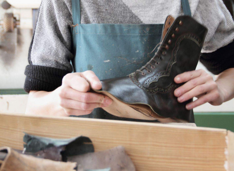 Nahaufnahme von Händen, die einen Stiefel machen - ein weiblicher Schuhschuster