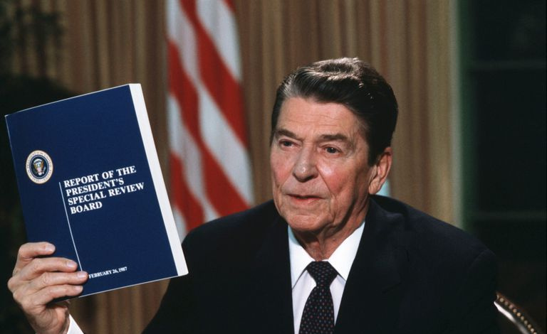President Ronald Reagan holder en kopi av Tower Commission-rapporten om Iran-Contra-skandalen
