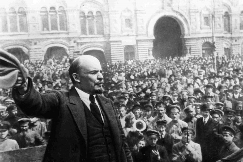 Vladimirs Iļjičs Ļeņins liela pūļa priekšā tur cepuri.
