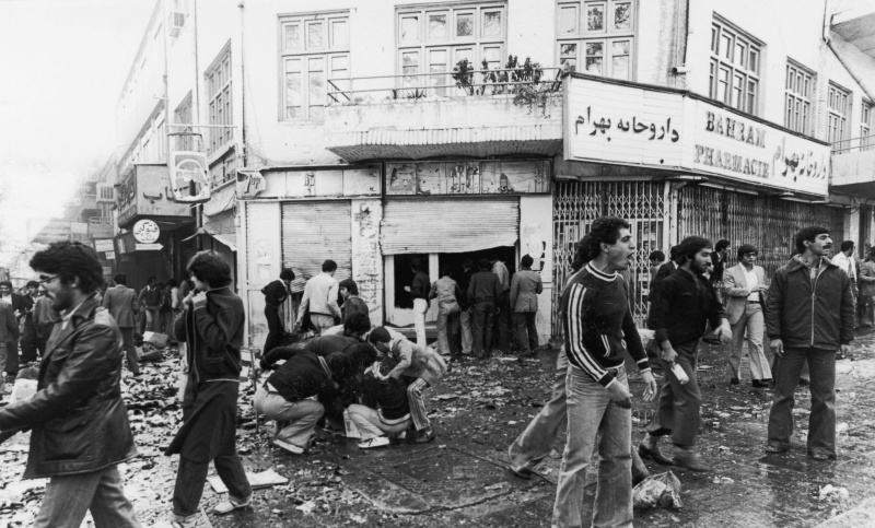 4. November 1978 Menschen versammeln sich um ein Opfer, während andere nach einem Aufstand in Teheran ein Geschäft plündern