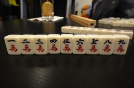 Strój postaci z zestawu płytek Mahjong siedzącego na stole.