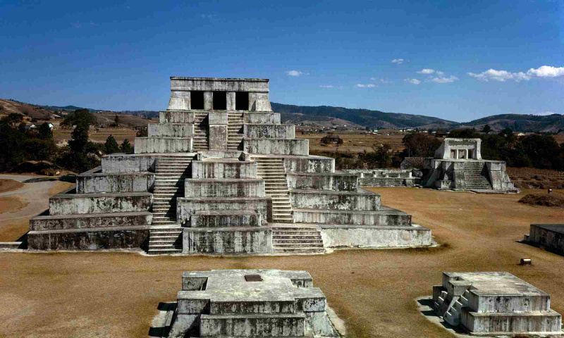 Las antiguas ruinas mayas de un complejo piramidal bajo un cielo azul.