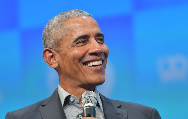 Barack Obama trzymając mikrofon i uśmiechając się.