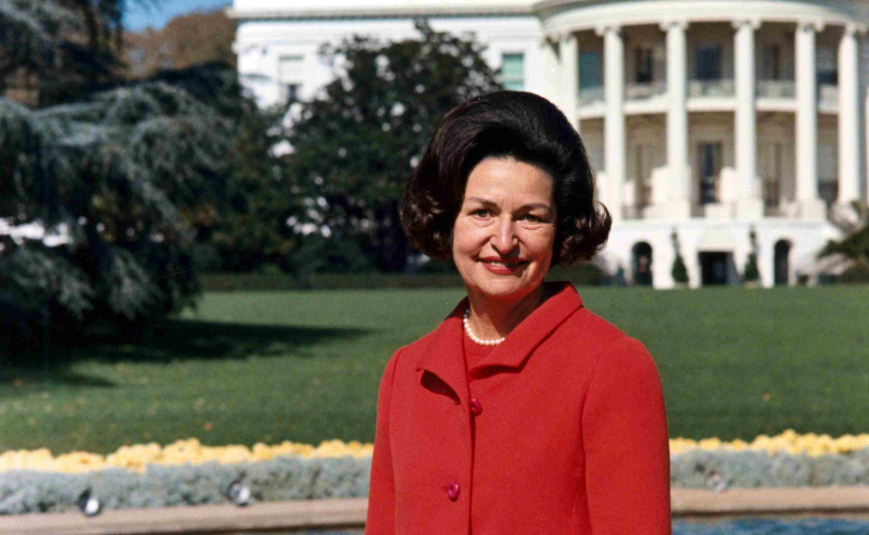 Fotografía en color de Lady Bird Johnson en el patio trasero de la Casa Blanca.