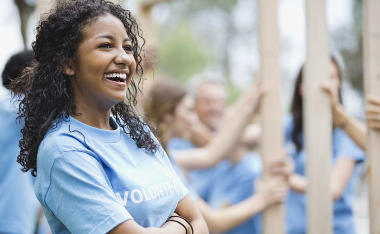 Adolescente alegre com voluntários construindo moldura de madeira no fundo