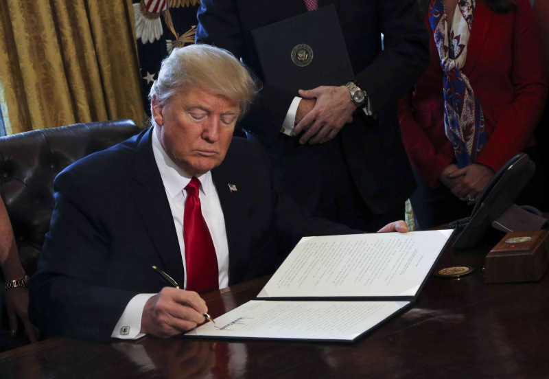 USAs president Donald Trump signerer utøvende ordrer, inkludert en ordre om å gjennomgå Dodd-Frank Wall Street for å rulle tilbake økonomiske reguleringer fra Obama-tiden.