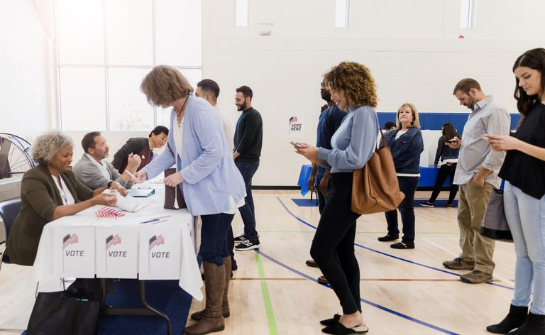 Mientras esperan en una larga fila, un grupo de votantes estudia sus teléfonos inteligentes.