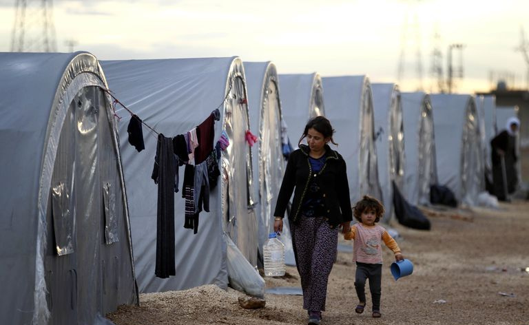 シリア難民は、トルコとシリアの国境にあるスルツ近くのテントの横を歩いています, 2014 Gokhan Sahin/Getty Images
