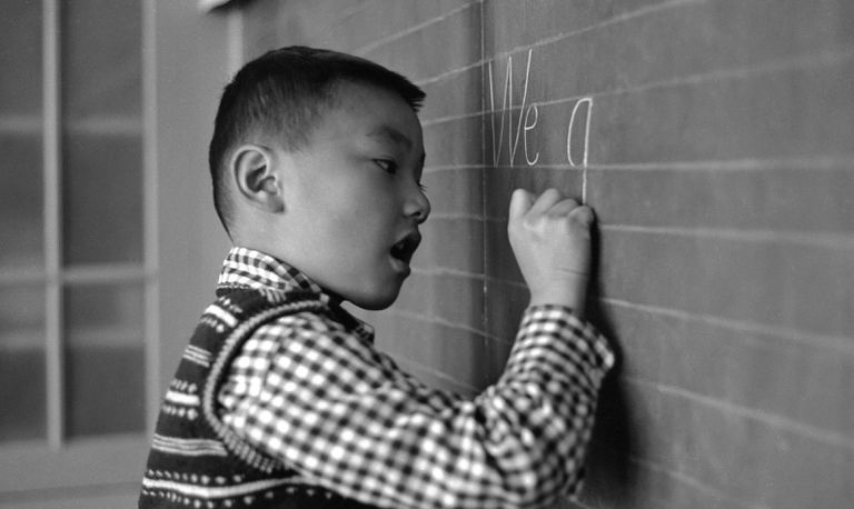 Un ragazzo scrive parole inglesi su una lavagna.