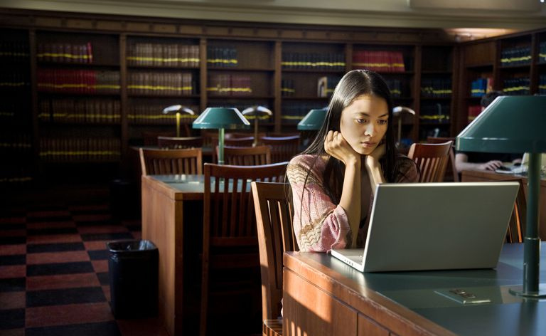 Une jeune femme utilise un ordinateur portable blanc dans la bibliothèque