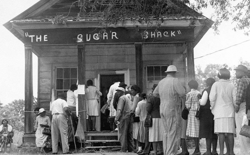 Gli elettori afroamericani, in grado di votare per la prima volta nella contea rurale di Wilcox, in Alabama, si mettono in fila davanti a un seggio elettorale dopo l