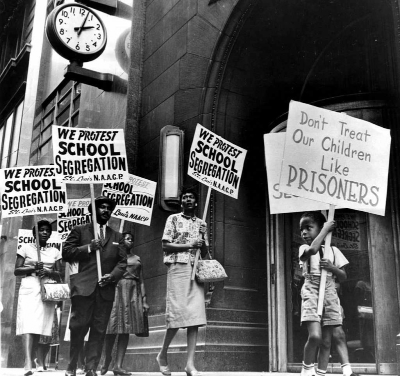 Demonstranti, starp tiem arī kāds jauns zēns, piketē pie skolas valdes biroja, protestējot pret segregāciju.