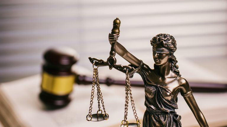 Nahaufnahme von Justitia gegen Hammer auf Buch