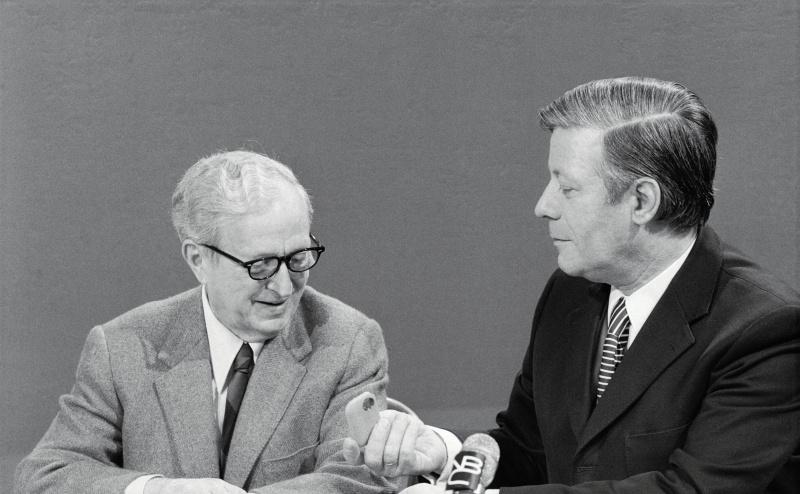Der westdeutsche Bundeskanzler Helmut Schmidt lädt Lawrence Spivak (links) zum Schnupftabak ein.