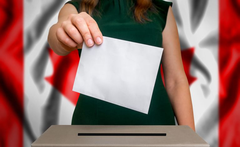 kobieta oddająca głos z kanadyjską flagą w tle