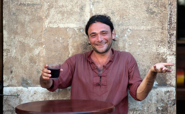 歩道のカフェでワインを飲むイタリア人男性