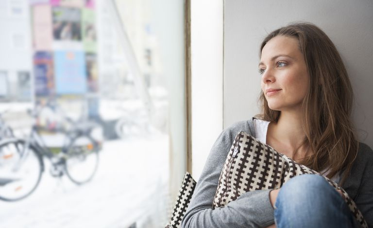 Frau träumt, während sie aus dem Fenster schaut