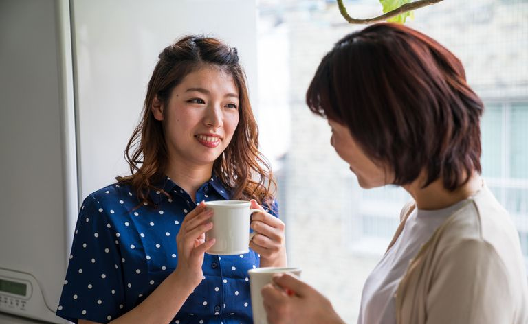 Mittlere erwachsene Tochter und ältere Mutter sprechen beim Kaffeetrinken