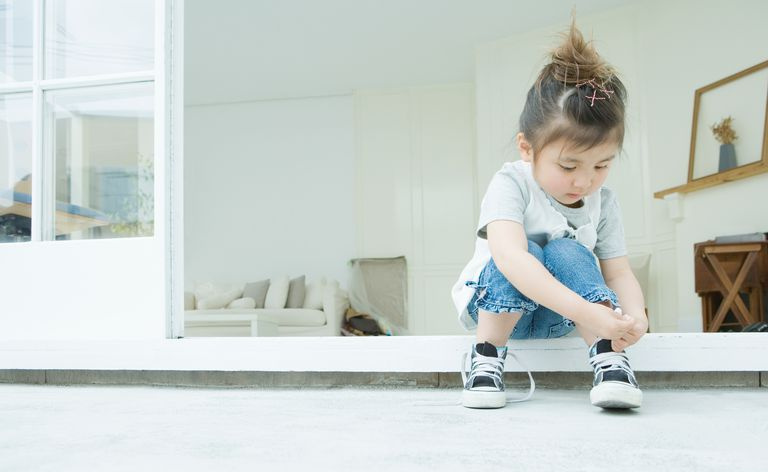 Ragazza che impara ad allacciarsi i lacci delle scarpe