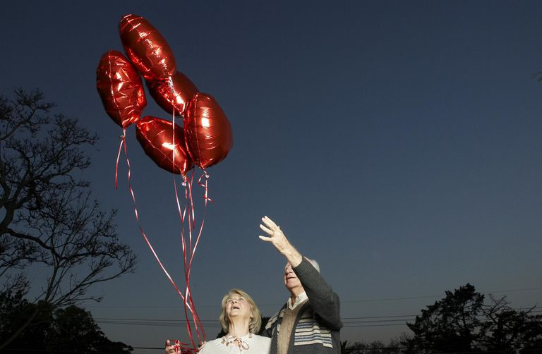 Starsza para z pękiem balonów w kształcie serca, patrząc w górę
