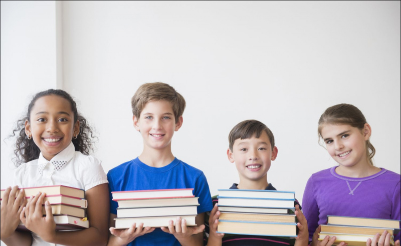 Foto von vier lächelnden Kindern, die Bücher halten