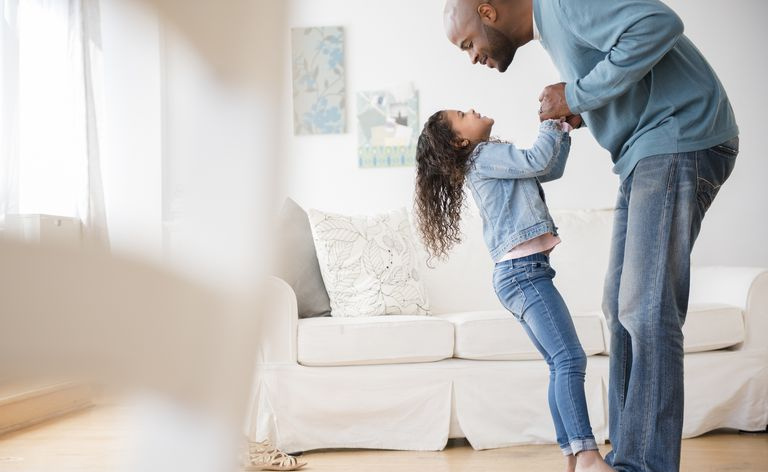 Filha de pé nos pés do pai e dançando