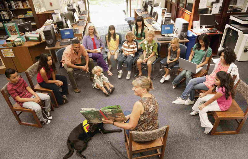 Bibliotekārs lasa grāmatu bērnu grupai
