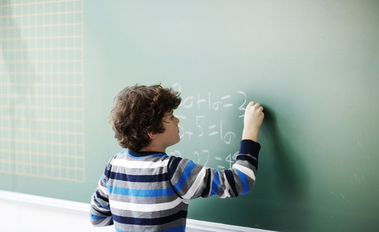 O menino escreve problemas de matemática no quadro-negro