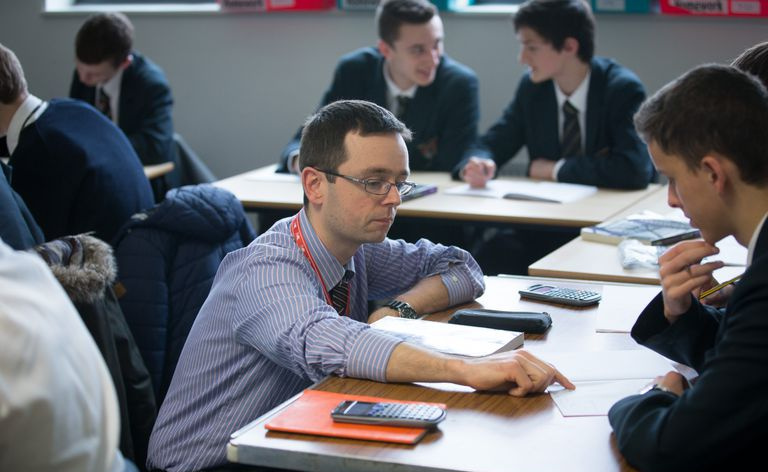 Skolotājs runā ar skolēnu matemātikas stundā