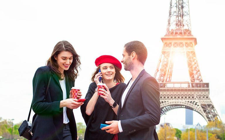 Amigos com smartphones perto da Torre Eiffel em Paris.