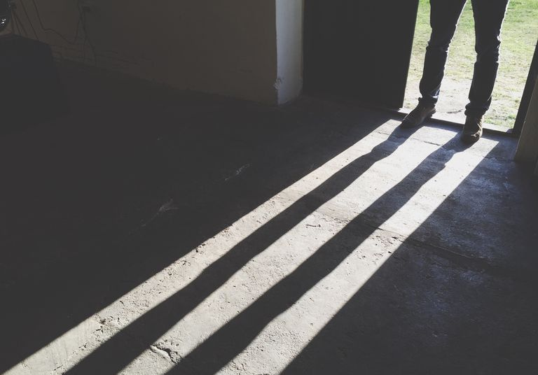 Niska sekcja mężczyzny stojącego w drzwiach przed cieniem w domu