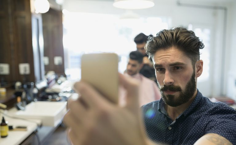 Bārdains vīrietis uzņem selfiju frizētavā