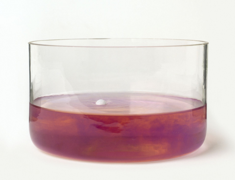 Natriummetall in einer Glasschale mit rotem Lackmuswasser, das Natriumhydroxid und Wasserstoff produziert