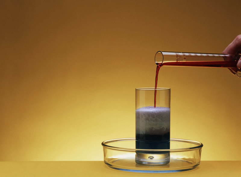 Hervorrufen einer chemischen Reaktion durch Gießen einer roten Flüssigkeit aus einem Reagenzglas in ein Glas, das eine andere Flüssigkeit enthält