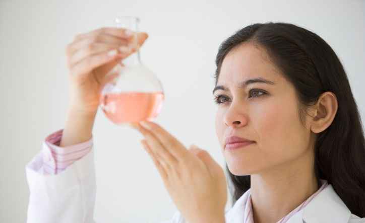 Diese Chemikerin hält eine Flasche Flüssigkeit.