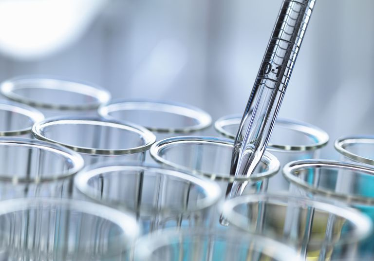Vista ritagliata della pipetta graduata che pipetta il liquido nelle provette