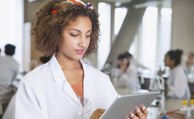 Étudiant concentré utilisant une tablette numérique dans une salle de classe de laboratoire scientifique